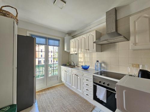 a kitchen with white cabinets and a large window at Atlantic & Teide Views Penthouse in Puerto de la Cruz