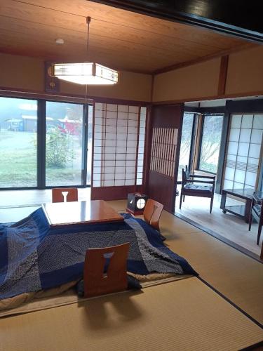 a room with a bed and a table and windows at ゲストハウス山音 in Takayama
