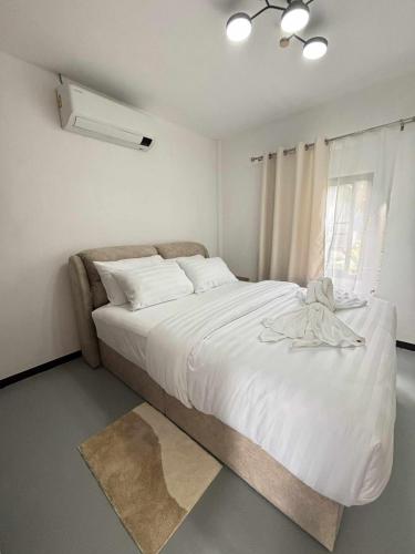 a bedroom with a large white bed with a window at Wasana Village Phutoei in Ban Phu Toei