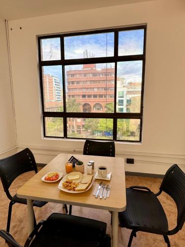 a table with plates of food on it in a room with a window at Hotel Plaza Mayor 44 in Medellín