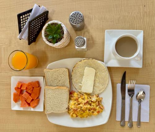 a plate of food with eggs bread and fruit and a cup of coffee at Hotel Plaza Mayor 44 in Medellín