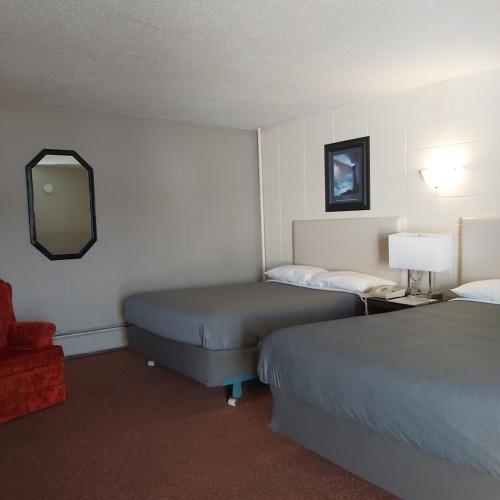 a hotel room with two beds and a mirror at Alpine Lodge Motel & Restaurant in Grande Cache