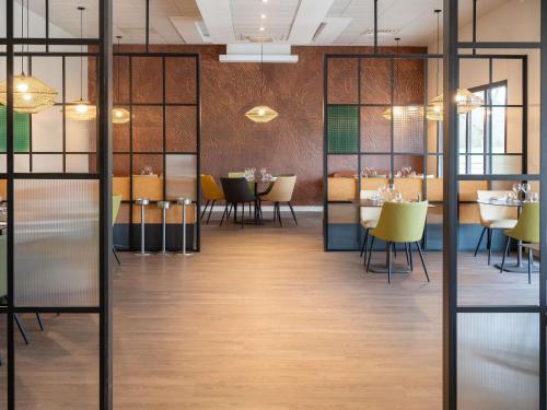 uma sala de jantar com mesas e cadeiras amarelas em Mercure Auxerre Autoroute du Soleil em Appoigny