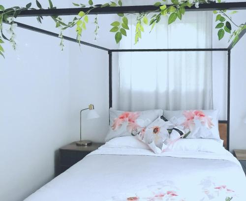 a bedroom with a bed with white sheets and pink flowers at Oohlala - High ceiling Peaceful Relaxing Bushland view in Mount Tamborine