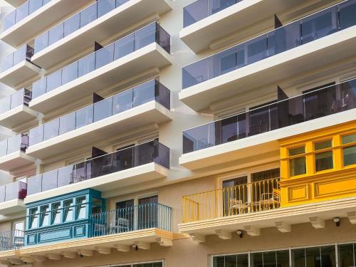 an apartment building with colorful balconies at Novotel Malta Sliema in Il-Gżira