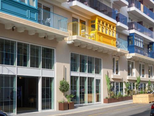 an apartment building with a yellow and blue balcony at Novotel Malta Sliema in Il-Gżira