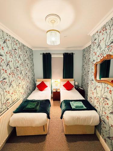 two beds in a hotel room with red pillows at Rock Ferry home in Birkenhead