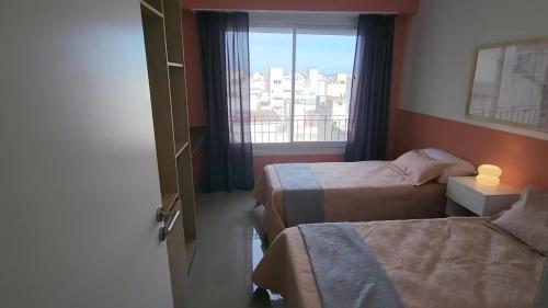 马德普拉塔Alquileres Corrientes的有两张床和一扇窗户的酒店房间