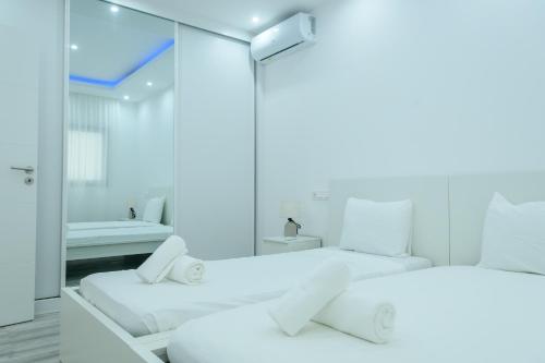 PrainhaEdifício Yes, Luxury 2 Bed Apartments, Praia, Cape Verde with Balcony and AC的白色客房的两张床,配有镜子