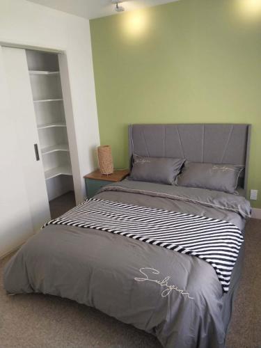 a bedroom with a large bed with a gray headboard at Oranga Comfort Stay in Auckland