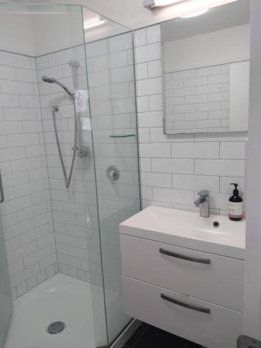a white bathroom with a shower and a sink at Oranga Comfort Stay in Auckland