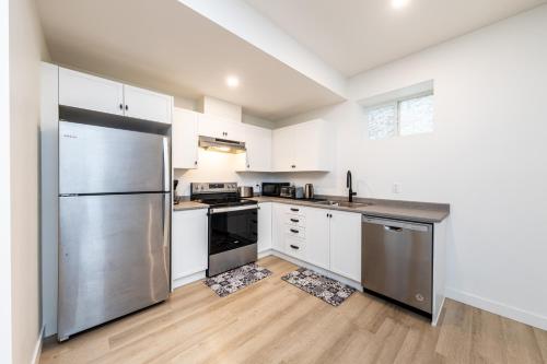 a kitchen with white cabinets and a stainless steel refrigerator at Sunflower Brandnew Cozy Private Suite in Langley