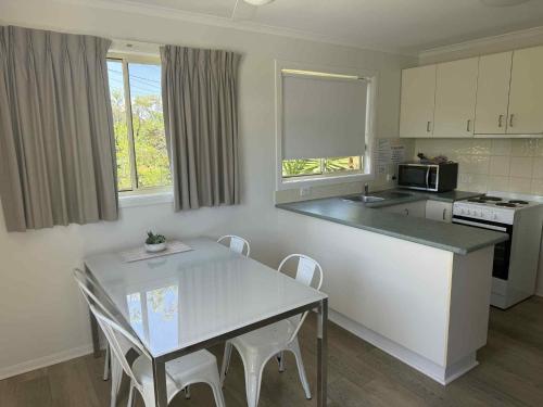 - une cuisine avec une table, une table et des chaises dans l'établissement Maclean Riverside Cabin Park, à Maclean