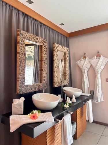 a bathroom with two sinks and two mirrors at Hotel Kia Ora Resort & Spa in Avatoru