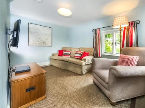 een woonkamer met een bank en een stoel bij Fursdon Cottage in Cadbury