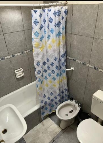 a bathroom with a shower curtain and a toilet and a sink at Casa Tina in Neuquén