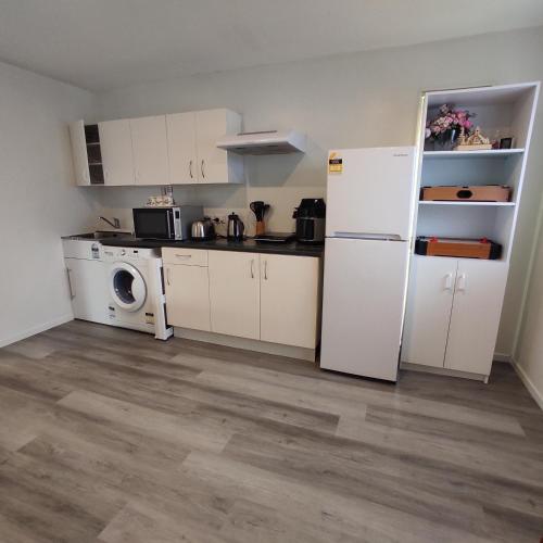 a kitchen with a refrigerator and a washing machine at Quiet 40m Studio - Kitchen, Washer, AC, Work Desk in Auckland