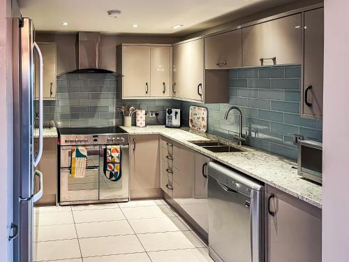 een keuken met roestvrijstalen apparatuur en grijze kasten bij Valentines Cottage - Uk48509 in Kirk Hammerton