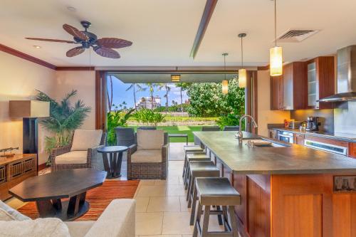 a kitchen with a bar with chairs and a table at Popular Ground Floor with Extra Grassy Area - Beach Tower at Ko Olina Beach Villas Resort in Kapolei