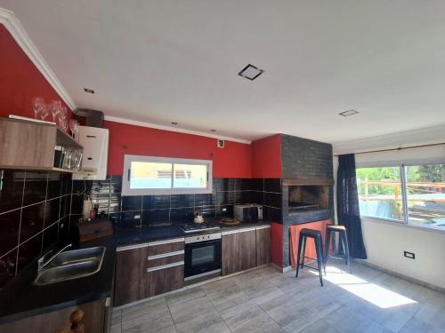 a kitchen with red walls and a stove top oven at Departamento Temporal en Villa Carlos Paz in Villa Carlos Paz