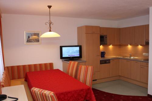 eine kleine Küche mit einem roten Tisch und einem TV in der Unterkunft Haflingerhof in Fiss