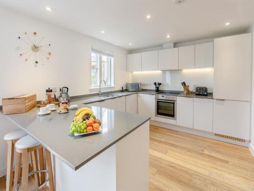 a white kitchen with a bowl of fruit on a counter at Lodge 52 Una in Carbis Bay