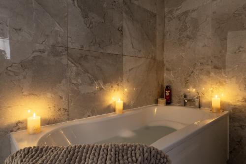 a bath tub with two candles in a bathroom at Skyway Luxury Stay with Jacuzzi in Bradford