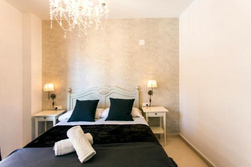 a bedroom with a bed with two tables and a chandelier at Total Valencia Old City Luxury in Valencia