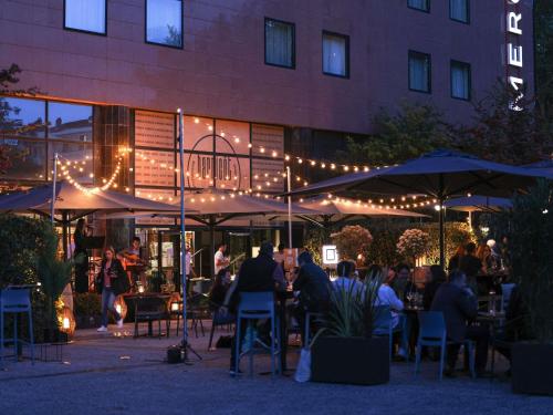 a group of people sitting at tables in front of a building at Hotel Mercure Toulouse Centre Compans in Toulouse