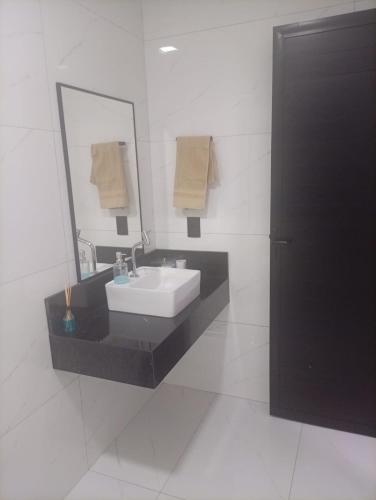 a white bathroom with a sink and a mirror at Espaço aconchegante com piscina e area gourmet in Foz do Iguaçu