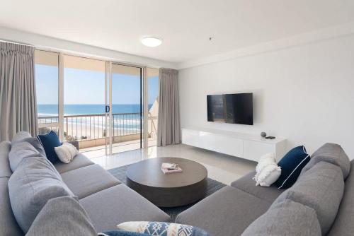 a living room with a large couch and a television at Allunga Stunning Beach Side Apartment in Gold Coast