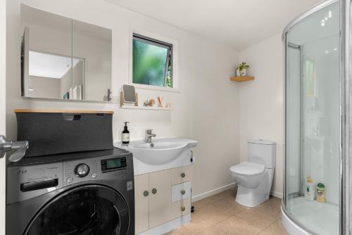 Waipu CoveTreetop Break - Waipu Cove Holiday Home的配有洗衣机和水槽的浴室