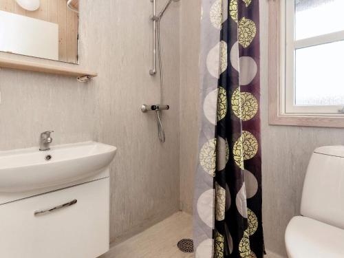 un bagno con lavandino e tenda da doccia di vast cabin in camping resort a Sønder Rubjerg
