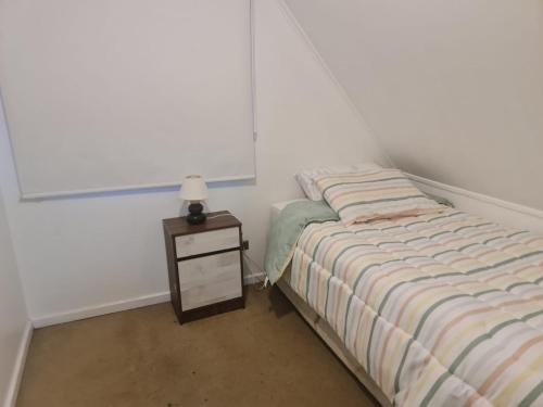 a small bedroom with a bed and a night stand at Sofia II in Valdivia