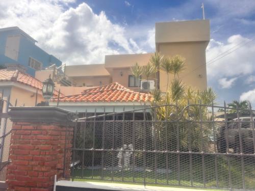 a fence in front of a house with a building at El descanso in Higuey