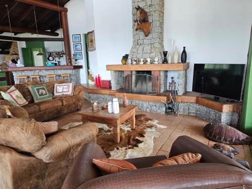 a living room with couches and a stone fireplace at Quarto com suite no Rancho São Francisco de Assis in Morretes