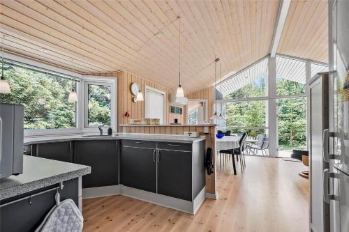 una cocina con armarios grises y un comedor con ventanas en HA141-Hals-Gyvelvej-3-B, en Hals