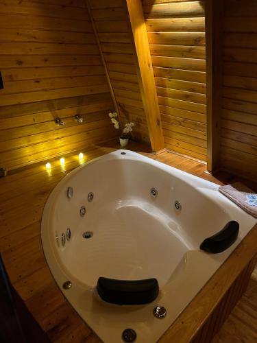 a bath tub in a wooden bathroom with lights at Cabana Encanto da Mata in Santa Maria do Erval