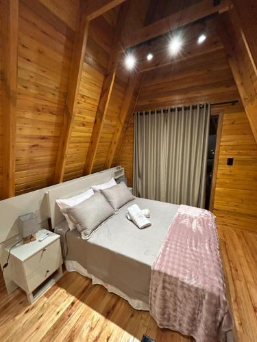 a bedroom with a bed in a room with wooden walls at Cabana Encanto da Mata in Santa Maria do Erval