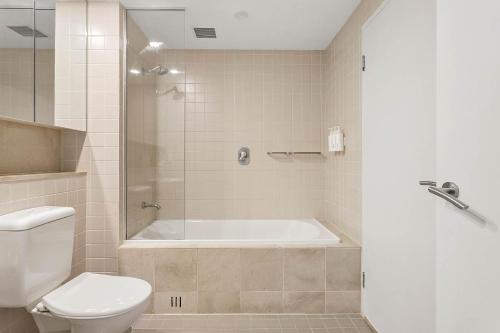 a bathroom with a bath tub and a toilet at Belle Escapes - Waves at The Bay in Glenelg