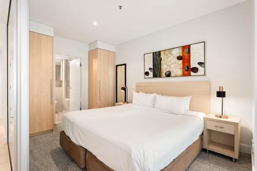 a bedroom with a large white bed in a room at Belle Escapes - Waves at The Bay in Glenelg
