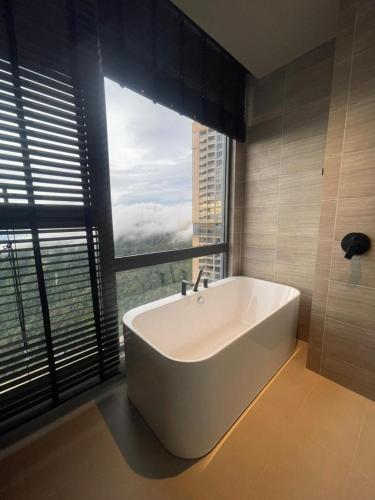 Una bañera en un baño con una ventana grande. en Antara Genting by Enigma 2BR, High Floor, en Genting Highlands