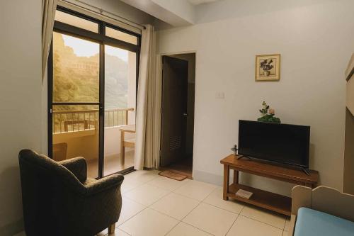 a living room with a television and a balcony at Wow unit 2 for 6 guests up to 8 in Baguio