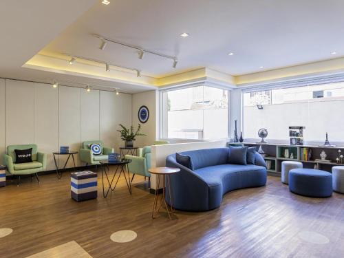 Una sala de estar con un sofá azul y sillas. en Mercure São Paulo Nações Unidas, en São Paulo