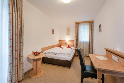 a bedroom with a bed and a desk and a table at Berghaus - Der Westerhof Hotel in Tegernsee