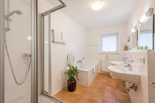 La salle de bains blanche est pourvue d'une douche et d'un lavabo. dans l'établissement Berghaus - Der Westerhof Hotel, à Tegernsee
