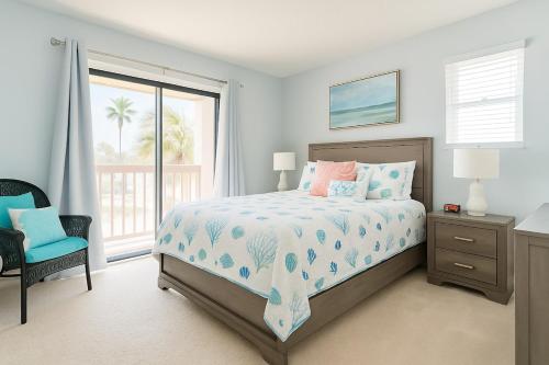 een slaapkamer met een bed, een stoel en een raam bij Beachside Bliss - Neptune Nook Unit 1 in Jacksonville Beach