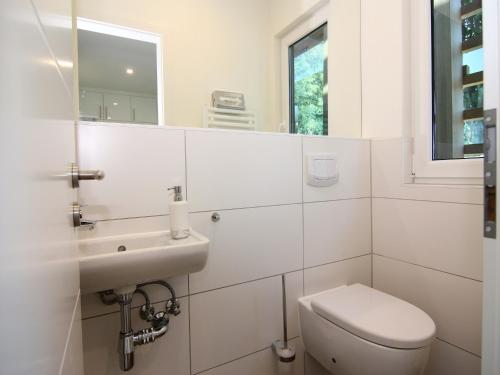 a white bathroom with a toilet and a sink at Chalet mit Außensauna in Wendorf in Wendorf