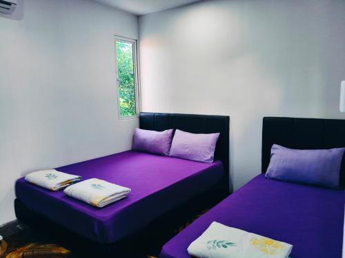 two beds in a room with purple sheets at Princess Iris Homestay in Penampang