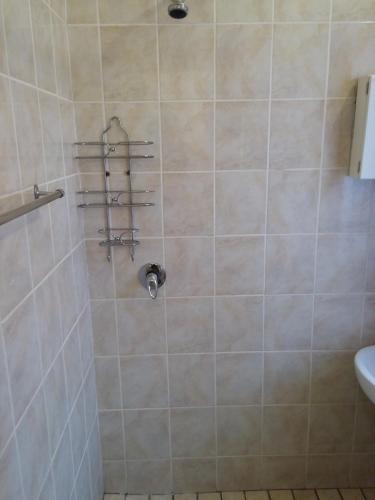 a bathroom with a shower with four towel racks at Uitenhage Apartments in Uitenhage